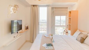 Une chambre d’hôtel avec un lit, une télévision, une fenêtre donnant sur un paysage agréable, une bibliothèque et un balcon.