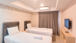 A hotel room with two beds, a flat-screen TV, and a ceiling-mounted air conditioner. - Cozy and Relaxing Studio Room at De Prima Apartment (Medan)