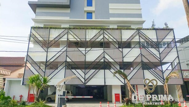A modern multi-story building with a distinctive zigzag balcony design, a gated entrance, and a visible parking area. - Cozy and Relaxing Studio Room at De Prima Apartment (Medan)