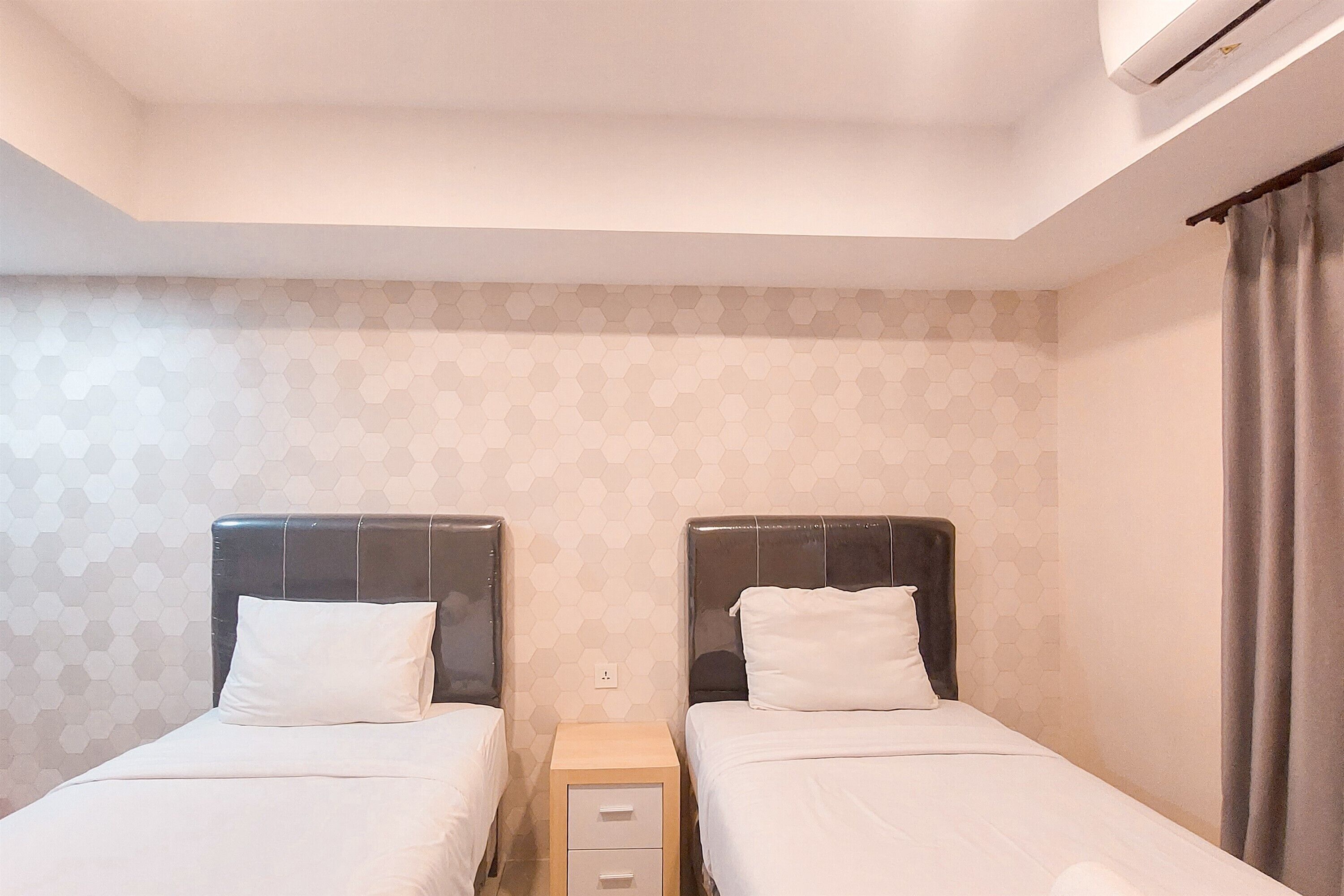 Een tweepersoonskamer met twee bedden, een nachtkastje en een wandairconditioner.