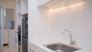 Une cuisine moderne avec des carreaux blancs, un évier en acier inoxydable et des appareils électroménagers intégrés.