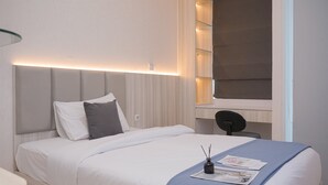 Une chambre d’hôtel moderne avec un lit bien fait, une table de chevet et une chaise.