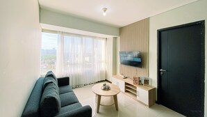A modern living room with a sofa, a coffee table, a TV mounted on the wall, and a door.