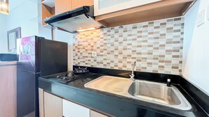 Una cocina moderna con encimera negra, pileta de acero inoxidable y salpicadero de azulejos.