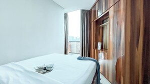 Una habitación de hotel con cama, vista a la ciudad y un armario de madera.
