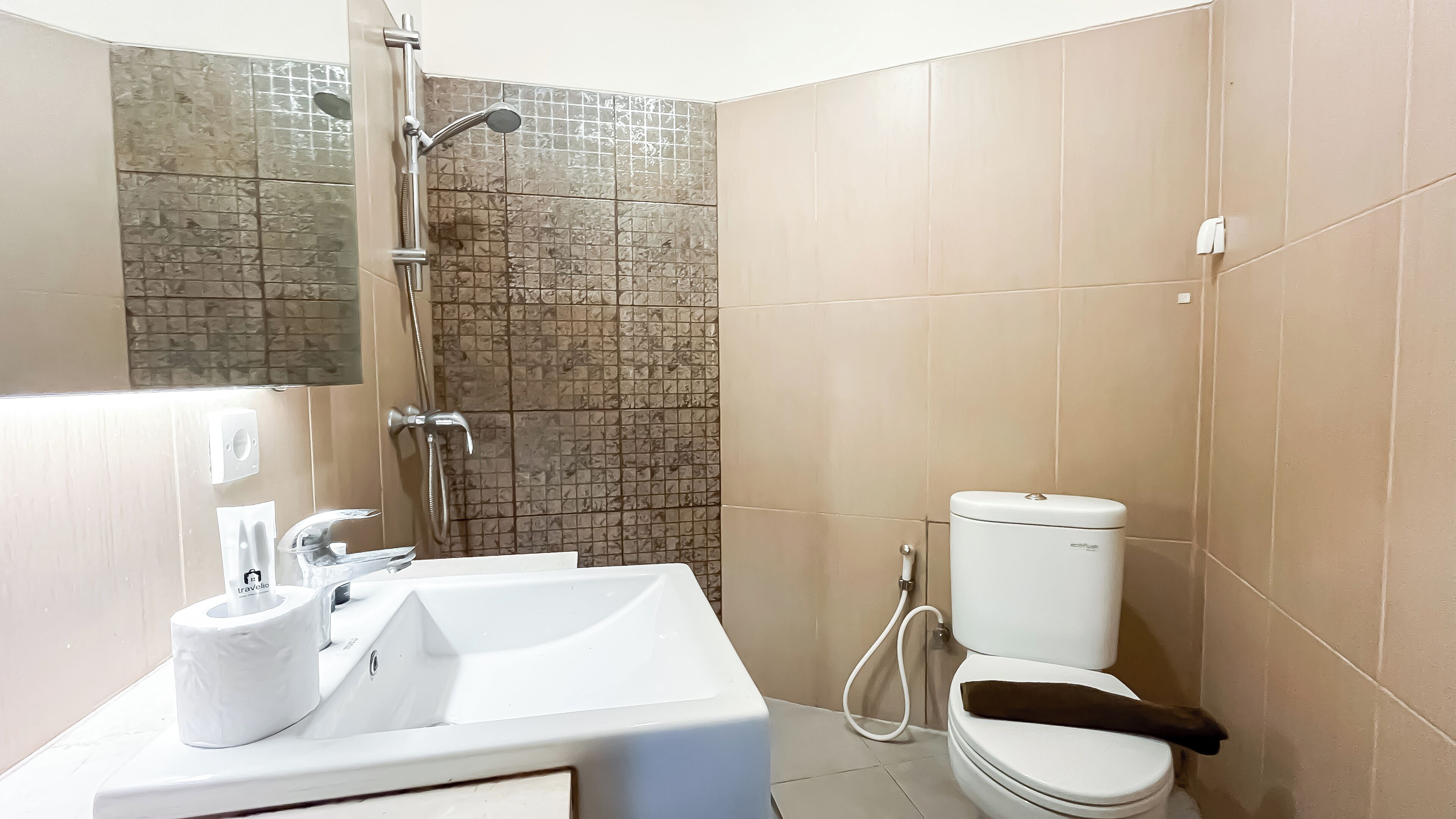 A bathroom with a shower, toilet, sink, and a toilet paper dispenser.