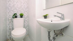 A bathroom with a toilet, sink, and two potted plants. - Cozy and Good Place Studio Apartment Tokyo Riverside PIK 2 (Teluknaga)