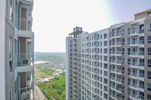 A high-rise building with multiple balconies and a view of a river and greenery below. - Cozy and Good Place Studio Apartment Tokyo Riverside PIK 2 (Teluknaga)