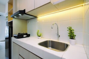 A modern kitchen with a stainless steel sink, white cabinetry, and two potted plants. - Cozy and Good Place Studio Apartment Tokyo Riverside PIK 2 (Teluknaga)
