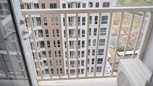Une vue depuis un balcon donnant sur un immeuble résidentiel à plusieurs étages, doté de balcons et de fenêtres.