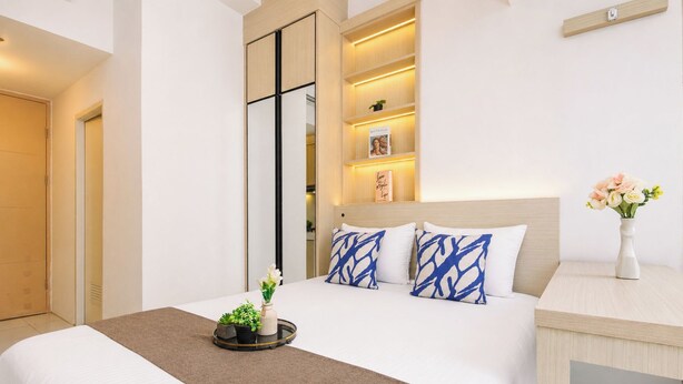 A hotel room with a bed, bedside table, and a nightstand. - Cozy and Good Place Studio Apartment Tokyo Riverside PIK 2 (Teluknaga)