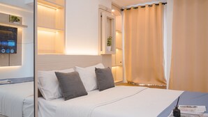 Une chambre d’hôtel moderne avec un lit bien fait, une table de chevet avec une lampe et un téléviseur fixé au mur.