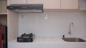 Une cuisine avec des carreaux blancs, un évier en acier inoxydable et une cuisinière à gaz Rinnai.