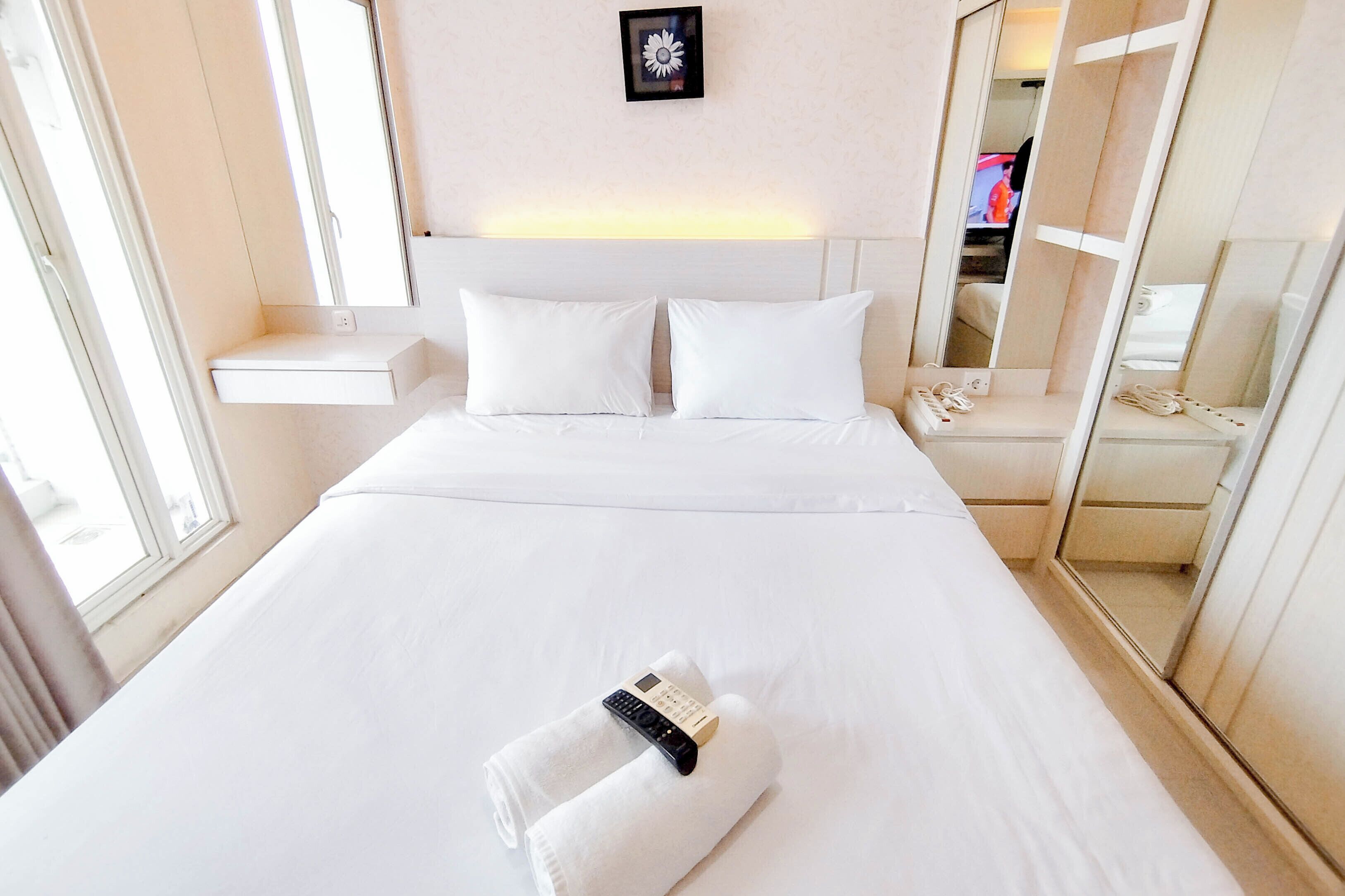Une chambre d’hôtel avec un grand lit, une table de chevet, un miroir et une fenêtre.