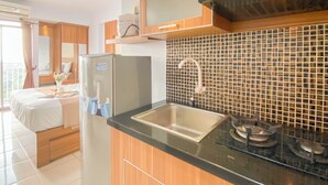 A modern kitchen with wooden cabinets, a stainless steel sink, and a tiled backsplash. - Nice and Cozy Studio at Bogor Valley Apartment (Bogor)