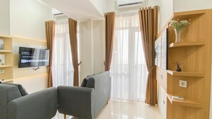 Ein modernes Wohnzimmer mit zwei grauen Sofas, einem an der Wand montierten Fernseher und einem Holzregal mit einer Vase.