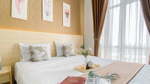Ein Hotelzimmer mit einem großen Bett, einem Nachttisch, einer Vase mit Blumen und einer Zeitschrift auf dem Bett.