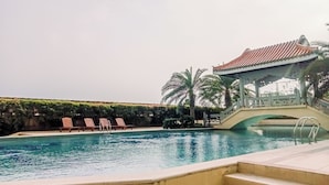A swimming pool with lounge chairs and a bridge. - Big and Cozy 3BR Apartment Lucky Tower Residence (Jakarta)