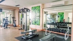A gym with exercise equipment, benches, and a rack of dumbbells. - Big and Cozy 3BR Apartment Lucky Tower Residence (Jakarta)