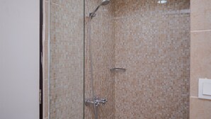 A shower with a glass door and tiled walls. - Comfy and Minimalist Studio (No Kitchen) Apartment Great Western (Tangerang)