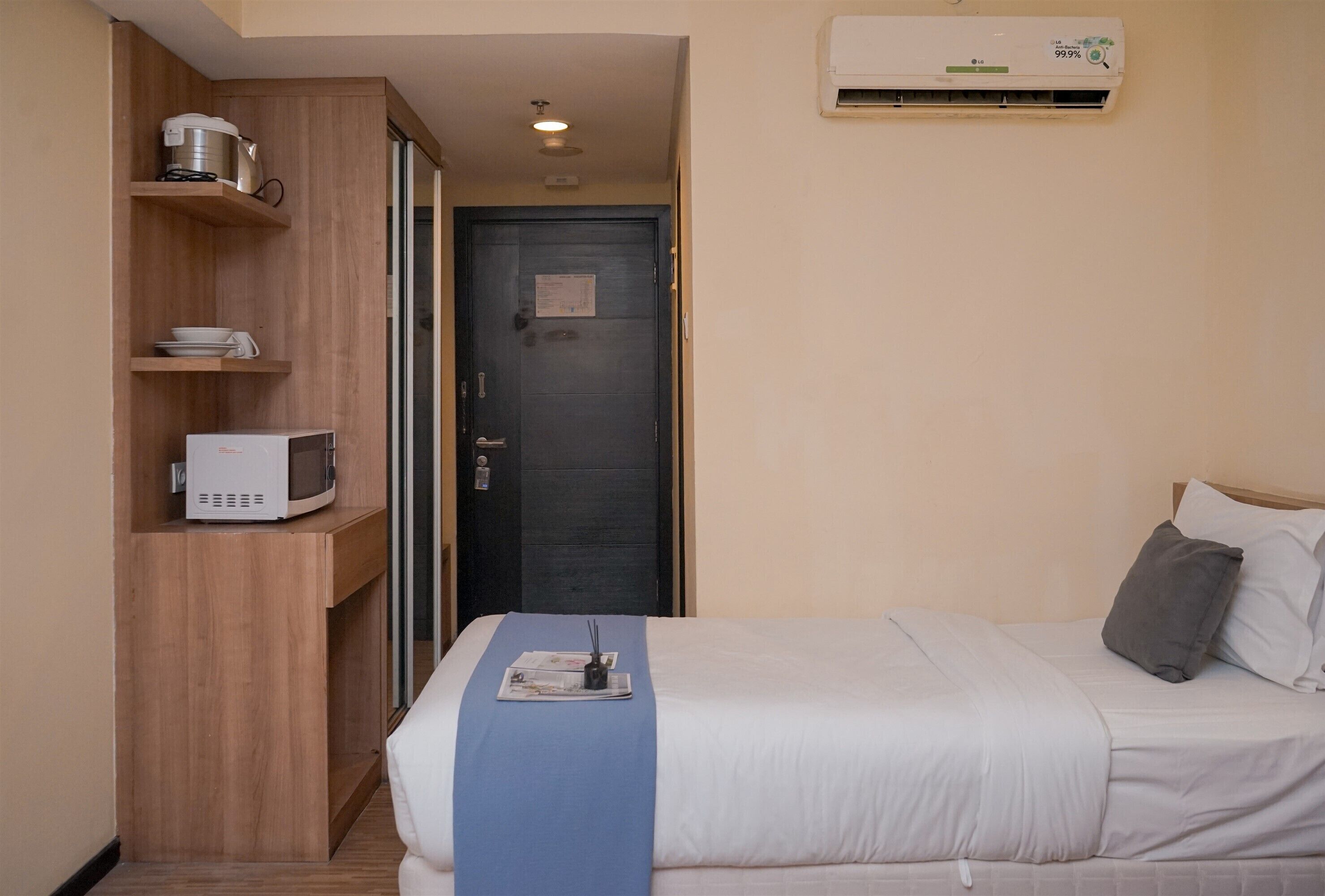 Hotellihuone, jossa on sänky, mikroaaltouuni, vedenkeitin ja ilmastointilaite.