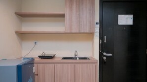 A compact kitchen with a sink, wooden cabinets, and a black door with a lock.