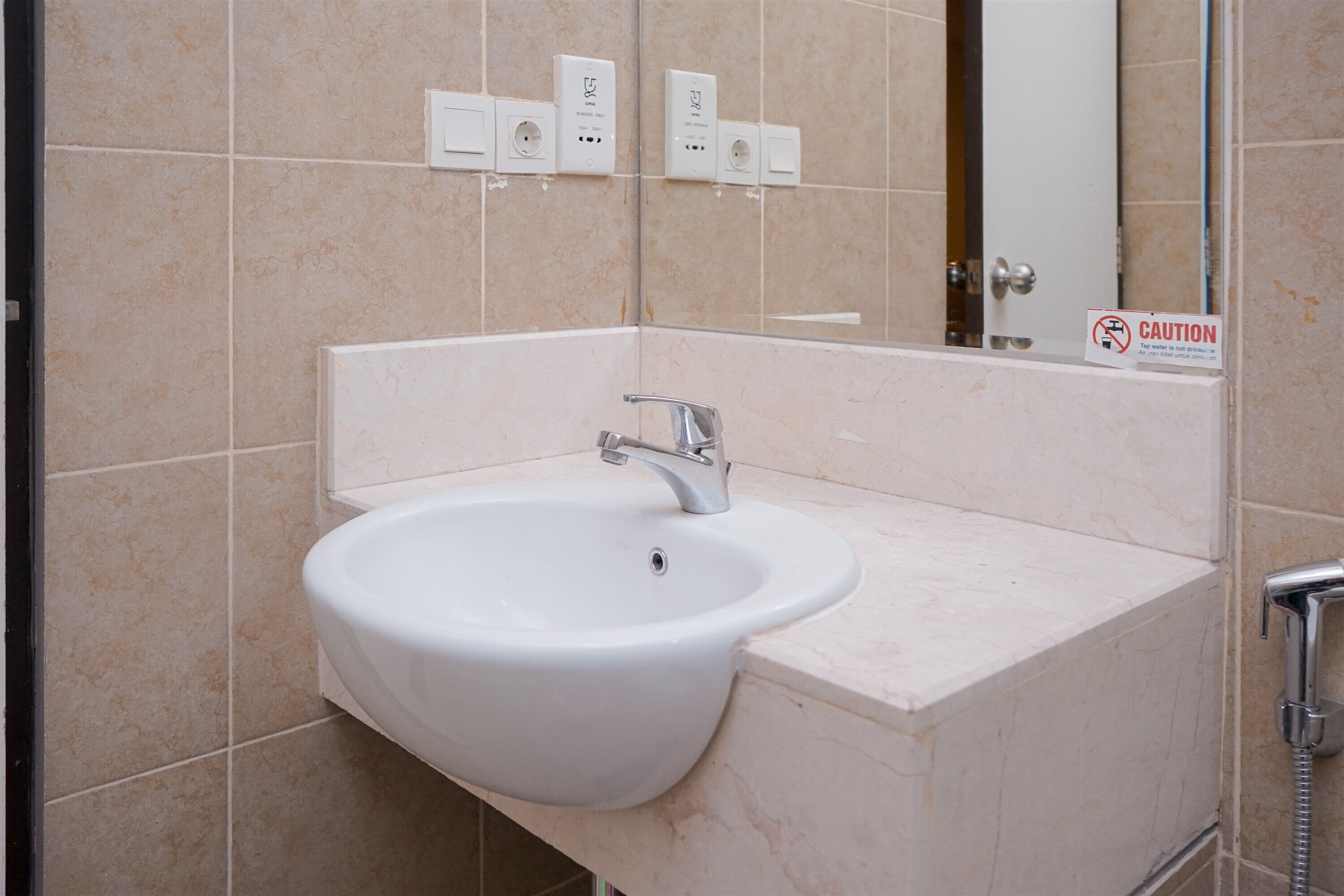 Un baño con un lavamanos blanco, un espejo y un letrero de precaución.