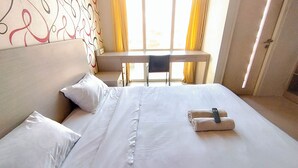 A hotel room with a bed, pillows, a desk, and a chair. - Modern Cozy Studio at The Square Surabaya Apartment (Surabaya)