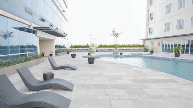 A rooftop pool area with lounge chairs and potted plants. - Modern Cozy Studio at The Square Surabaya Apartment (Surabaya)