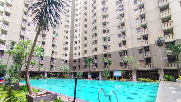 A high-rise residential building with a swimming pool in the courtyard.