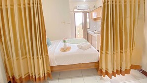 A hotel room with a bed, curtains, a window, a sink, and a ceiling fan.