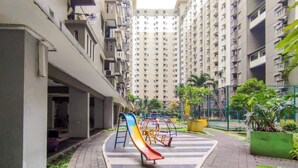 A playground with slides and swings in a residential area with high-rise buildings.