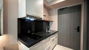 Una cocina compacta con encimera negra, pileta de acero inoxidable y horno integrado.