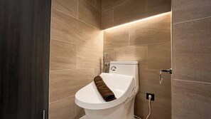 A modern bathroom with a toilet, a shower, and a towel. - Comfy and Spacious Studio Apartment Carstensz Residence (Gading Serpong)