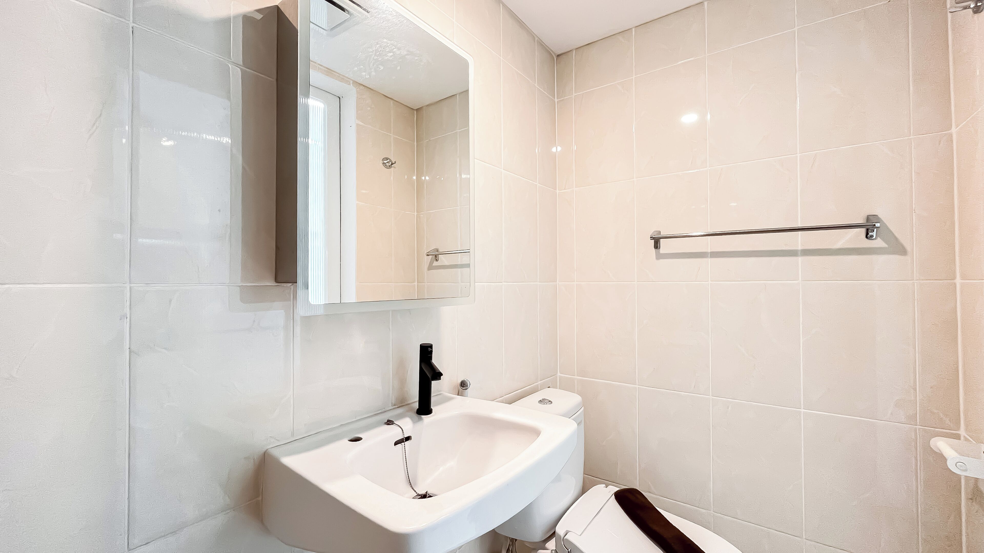 A modern bathroom with a white sink, mirror, and towel rack.
