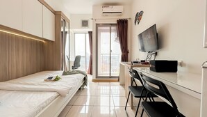 A hotel room with a bed, a desk with a chair, a television, and a sliding door to a balcony.