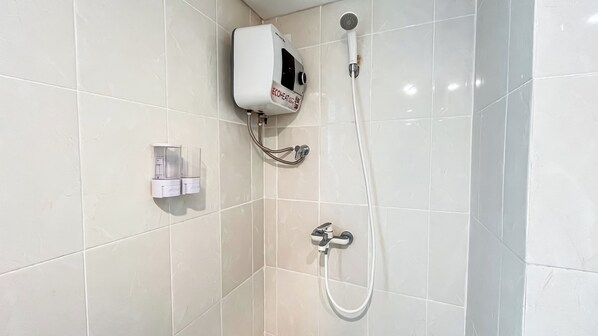 A bathroom with a wall-mounted shower, a hand dryer, and a soap dispenser.