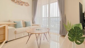 Ein modernes Wohnzimmer mit einer Couch, einem Couchtisch und einem großen Fenster mit Vorhängen.
