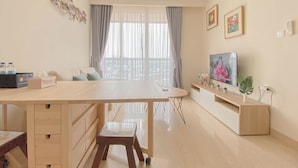 Ein modernes Wohnzimmer mit einem großen Holztisch, einem Fernseher und Blick auf einen Balkon.