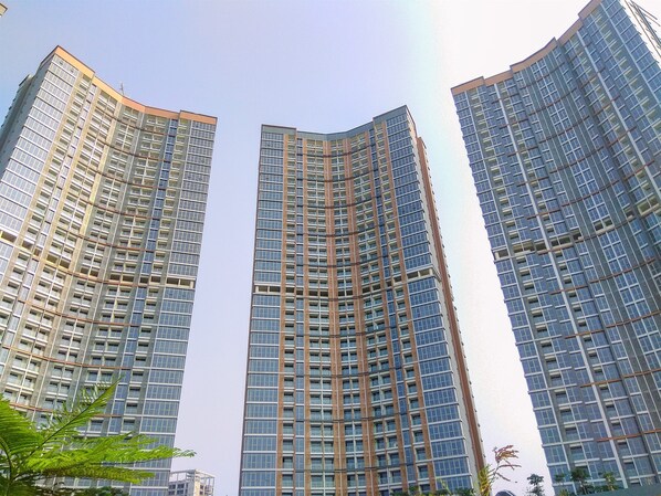 Three high-rise buildings with a modern architectural design, featuring a grid of windows and a curved facade.