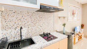 Eine Küche mit geflecktem Fliesenspiegel, einem schwarzen Spülbecken, einem Herd und einem Holzschrank.