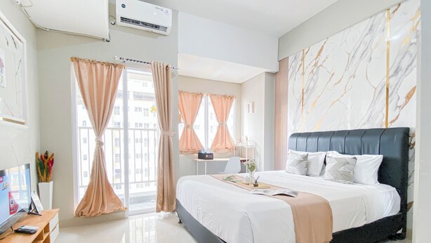 Ein modernes Hotelzimmer mit einem großen Bett, einem Flachbildfernseher, einem Schreibtisch und einem Fenster mit Vorhängen.