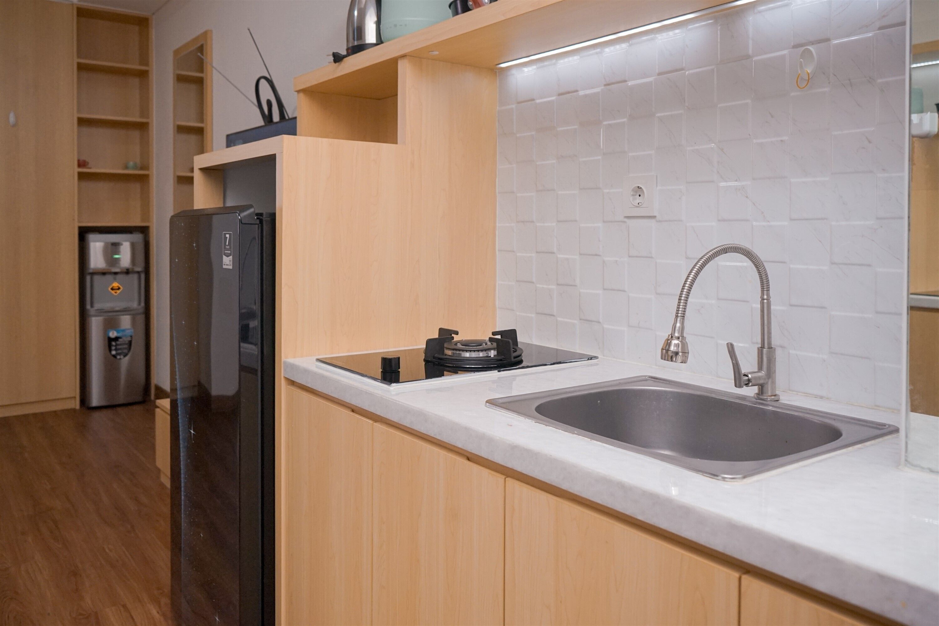 A modern kitchen with a stainless steel sink, wooden cabinets, and a built-in gas stove.