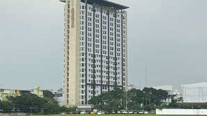 A tall, rectangular hotel building with a flat roof and a sign at the top. - Cozy Studio at Atria Residence Gading Serpong Apartment (Gading Serpong)