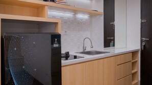 A modern kitchen with a built-in refrigerator, a sink, and wooden cabinets. - Cozy Studio at Atria Residence Gading Serpong Apartment (Gading Serpong)