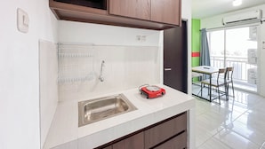 Una cocina con un lavamanos de acero inoxidable, un calentador portátil rojo y armarios de madera.
