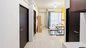 A hallway with a dining area, featuring a table and chairs, a wooden cabinet, and a sliding glass door leading to a balcony.