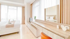 Une chambre d’hôtel moderne avec un lit, un bureau en bois, un grand miroir et une vue sur la ville.