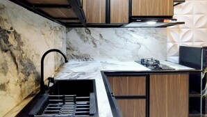 A kitchen with marble countertops, wooden cabinets, and a black faucet. - Cozy and Spacious 1BR at Anderson Supermall Mansion Apartment (Surabaya)