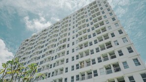 A tall, white multi-story building with numerous balconies and windows.